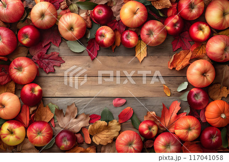 Autumn-themed arrangement of fresh apples and colorful fall leaves on a wooden background, perfect for Thanksgiving decor 117041058