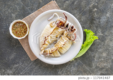 Grilled squid (Cuttlefish) with spicy and sour sauce on white plate, a popular Asian seafood dish. 117041487