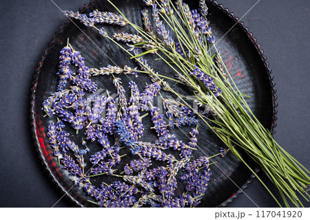Freshly harvested lavender flowers displayed beautifully on a dark ornate plate. 117041920