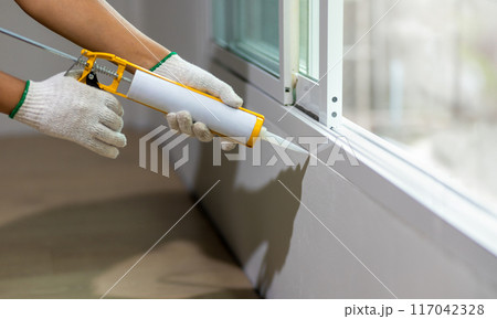 Construction worker using silicone sealant caulk the outside window frame. Construction worker using silicone sealant caulk the outside window frame. 117042328