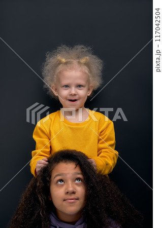 funny little girl with fair fluffy hair doing her sister hair funny little girl with fair fluffy hair doing her sister hair 117042504