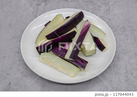長方形にカットされた夏野菜の茄子　切られた茄子が丸い皿にのせられている 117044043