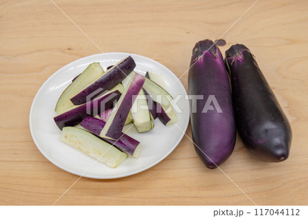 二本の茄子とカットされて皿にのせられている茄子　 117044112