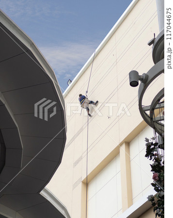Worker on Ropes Painting Building Exterior. Worker on Ropes Painting Building Exterior. 117044675