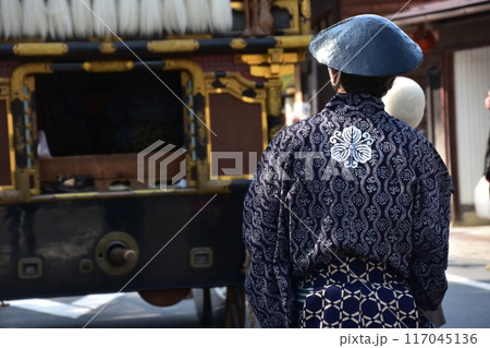 日本の岐阜県高山市　春の高山祭　屋台と呼ばれる豪華な山車　法被を着て陣笠を被っている男性の後ろ姿 117045136
