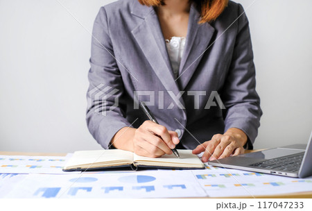 Asian businesswoman sit at their desks and calculate financial graphs showing results about their investments and plan successful business growth process 117047233