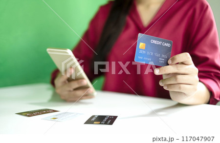 Asian girl shopping online holding credit and using smartphone enter their card number in the mobile phone app to purchase and payment in internet store Asian girl shopping online holding credit and using smartphone enter their card number in the mobile phone app to purchase and payment in internet store 117047907