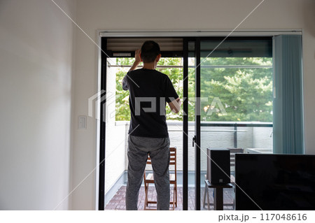 部屋のサッシを開けている男性の後ろ姿 部屋のサッシを開けている男性の後ろ姿 117048616