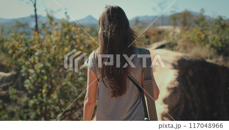 Woman tourist traveler walking Pai Canyon Kong Lan, Chiang Mai Province, Thailand. Long hair brunette with bag back view, slow motion 117048966