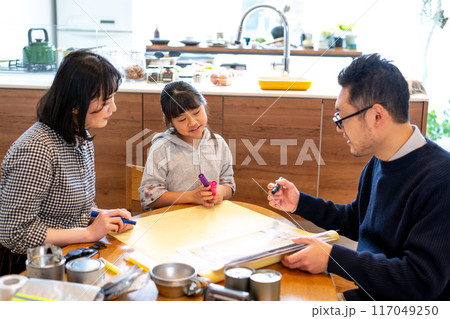 お父さんが見せるハザードマップを眺めながら思案する娘とそれを見守るお母さん 117049250