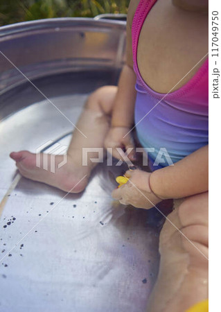 baby in a metal tub plays with rubber ducklings in the summer garden baby in a metal tub plays with rubber ducklings in the summer garden 117049750