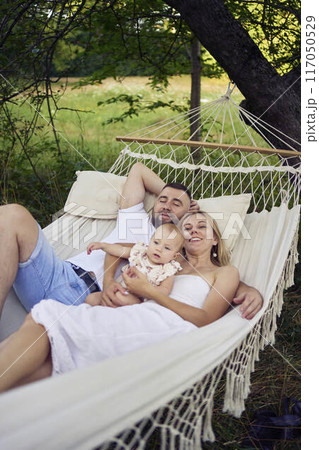 a loving couple with their baby girl in a hammock 117050529