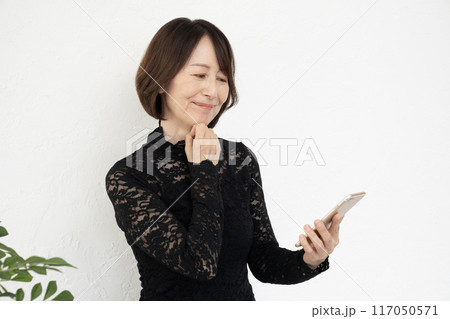 スマホを見て微笑むミドル女性 117050571