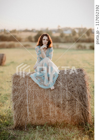 sexy young topless nude girl sitting on haystack in field in summer. Added the effect of a small film grain 117052392