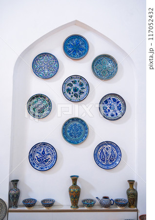 traditional Arabic Uzbek ceramic plate with hand-painted Islamic arabesque pattern on wall at oriental tableware market 117052432