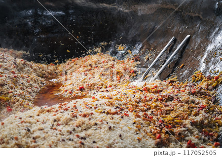 oriental dish of Uzbek cuisine is rice pilaf with vegetables and spices in cauldron in kitchen of Asian restaurant in Tashkent Pilaf Center Besh Qozon in Uzbekistan close-up 117052505