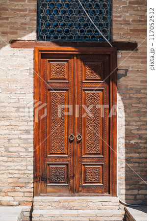 Uzbek carved wooden door to Kukeldash Madrasah with traditional pattern oriental ornaments in Uzbekistan in Tashkent Uzbek carved wooden door to Kukeldash Madrasah with traditional pattern oriental ornaments in Uzbekistan in Tashkent 117052512