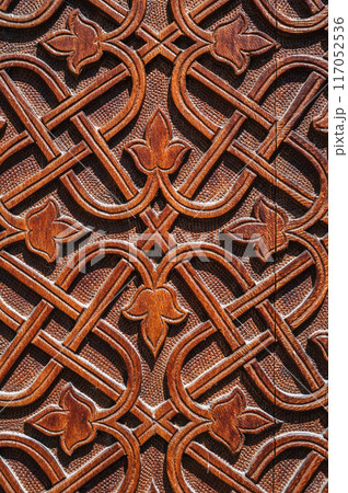 floral oriental uzbek carved ornament pattern on brown wooden door in Uzbekistan in Tashkent close-up 117052536