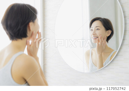 洗面所で鏡を見るミドルの女性　 117052742