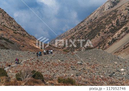landscape with a group of tourists traveling people in an autumn orange valley in mountains in fall 117052746