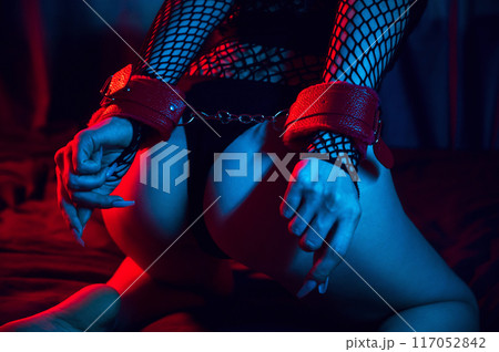 submissive woman with a sexy body and ass with hands in BDSM handcuffs is sitting on bed in bedroom. Slave girl in lingerie for sex with submission and domination submissive woman with a sexy body and ass with hands in BDSM handcuffs is sitting on bed in bedroom. Slave girl in lingerie for sex with submission and domination 117052842