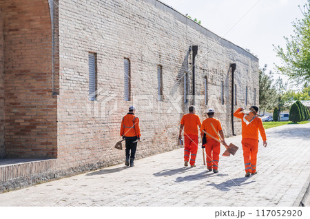group of Uzbek male janitors in orange uniforms with shovels in summer on street in city of Tashkent in Uzbekistan 117052920