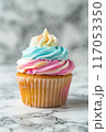 A cupcake with a swirl of pink, blue, and yellow frosting 117053350