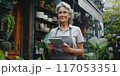 A woman in a flower shop holding a tablet 117053351