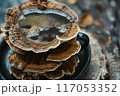 A cup of coffee is sitting on a wooden table with a pile of mushrooms on top of 117053352