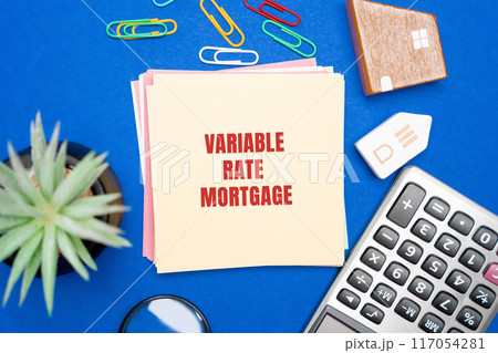 Variable rate mortgage concept. Type of home loan in which the interest rate is not fixed. Real estate, business and finance concept. Miniature houses, magnifying glass, calculator and notes 117054281