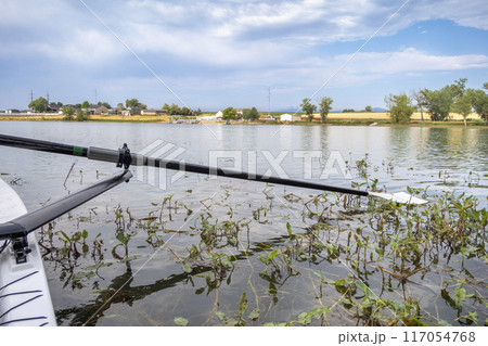 hatchet sculling oar on a calm lake with water weeds, Boyd Lake in Colorado hatchet sculling oar on a calm lake with water weeds, Boyd Lake in Colorado 117054768
