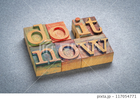 do it now - motivational text in retro letterpress wood type stained by color inks, productivity concept 117054771