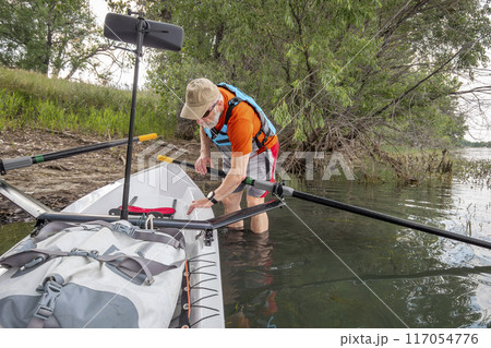 senior man with a rowing shell on a shore of a lake in Colorado senior man with a rowing shell on a shore of a lake in Colorado 117054776
