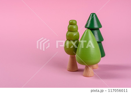Wooden model of a tree with a green crown and trunk on a pink background 117056011