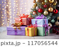 Festive gifts beside a glowing Christmas tree 117056544
