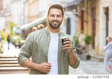 Young man guy enjoying drinking morning coffee hot drink, relaxing, taking a break in city street Young man guy enjoying drinking morning coffee hot drink, relaxing, taking a break in city street 117057738