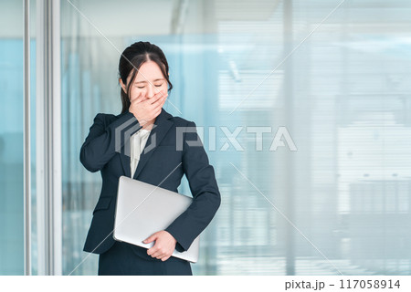 オフィスビルの前でショック・驚きで顔を覆う若いアジア人ビジネスウーマン（悲しい・リストラ・泣く） 117058914