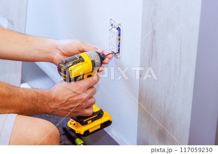 Installing an outlet with screwdriver in house during reconstruction Installing an outlet with screwdriver in house during reconstruction 117059230