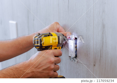 Electrician install outlet at wall in house during reconstruction Electrician install outlet at wall in house during reconstruction 117059234