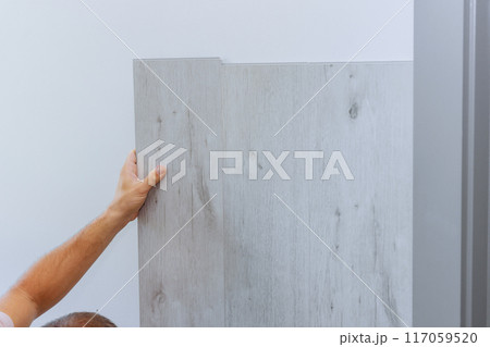 Installation of laminated panels on wall at room house during reconstruction Installation of laminated panels on wall at room house during reconstruction 117059520