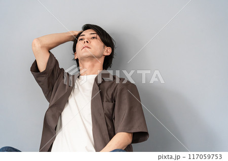 椅子に座り考え事をする若いアジア人男性（悩む・落ち込む・ネガティブ・将来・後悔・転職・就職・学歴） 117059753