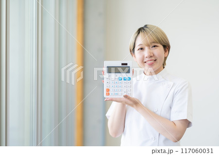 電卓を持つ金髪ショートヘアの若い女性整体師（髪色自由、自分らしく働く、職場環境） 117060031