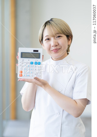 電卓を持つ金髪ショートヘアの若い女性整体師（髪色自由、自分らしく働く、職場環境） 117060037