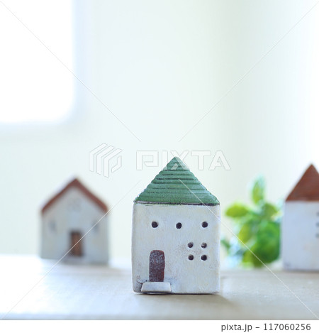 小さな家の模型を窓際に置いた光あふれるやわらかなマイホームのイメージ 117060256