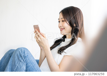 ソファーでスマホを見る女性 117063250
