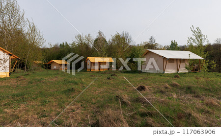 Cozy open glamping tents with light inside in summer camp. Camping tent for holiday and vacation 117063906
