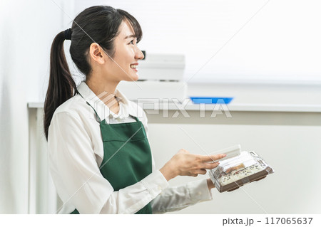 コンビニ・スーパーで端末を使って在庫管理をする店員・バイトの女性 117065637