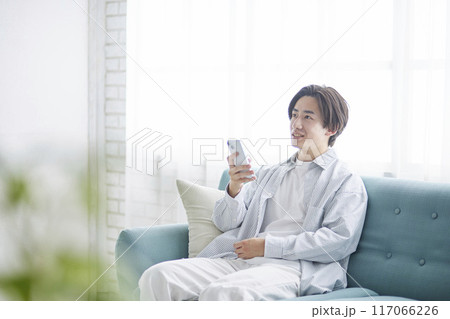 リビングのソファーリラックスしスマートフォンを使用する日本人の男性 リビングのソファーリラックスしスマートフォンを使用する日本人の男性 117066226