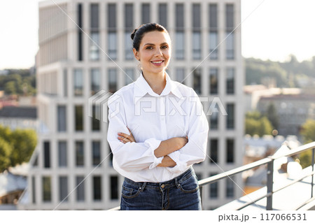 Confident businesswoman standing with arms crossed on rooftop Confident businesswoman standing with arms crossed on rooftop 117066531