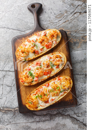 Baked Cheesy Shrimp Garlic Bread with mozzarella, tomatoes and parsley closeup on the wooden board. Vertical top view Baked Cheesy Shrimp Garlic Bread with mozzarella, tomatoes and parsley closeup on the wooden board. Vertical top view 117069071